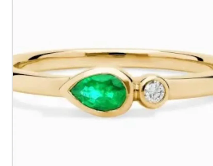 Emerald and diamond gold ring on a clean backdrop